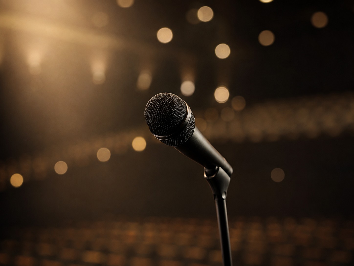 Bühnenmikrofon im warmen Spotlight – Symbol für Stimme, Präsenz und Human Connection
